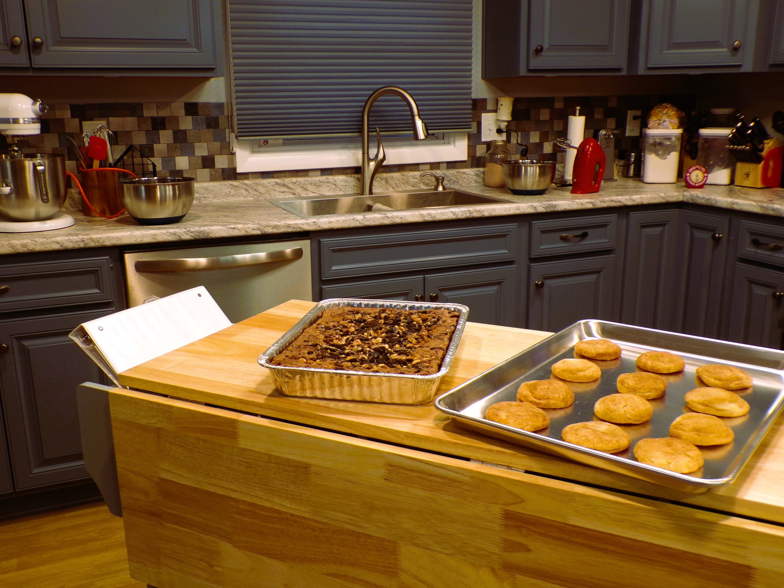 Freshly baked chocolate chip cookies and a pan of brownies cooling on a wooden countertop.