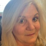 Close-up portrait of a woman with blonde hair and a subtle smile.