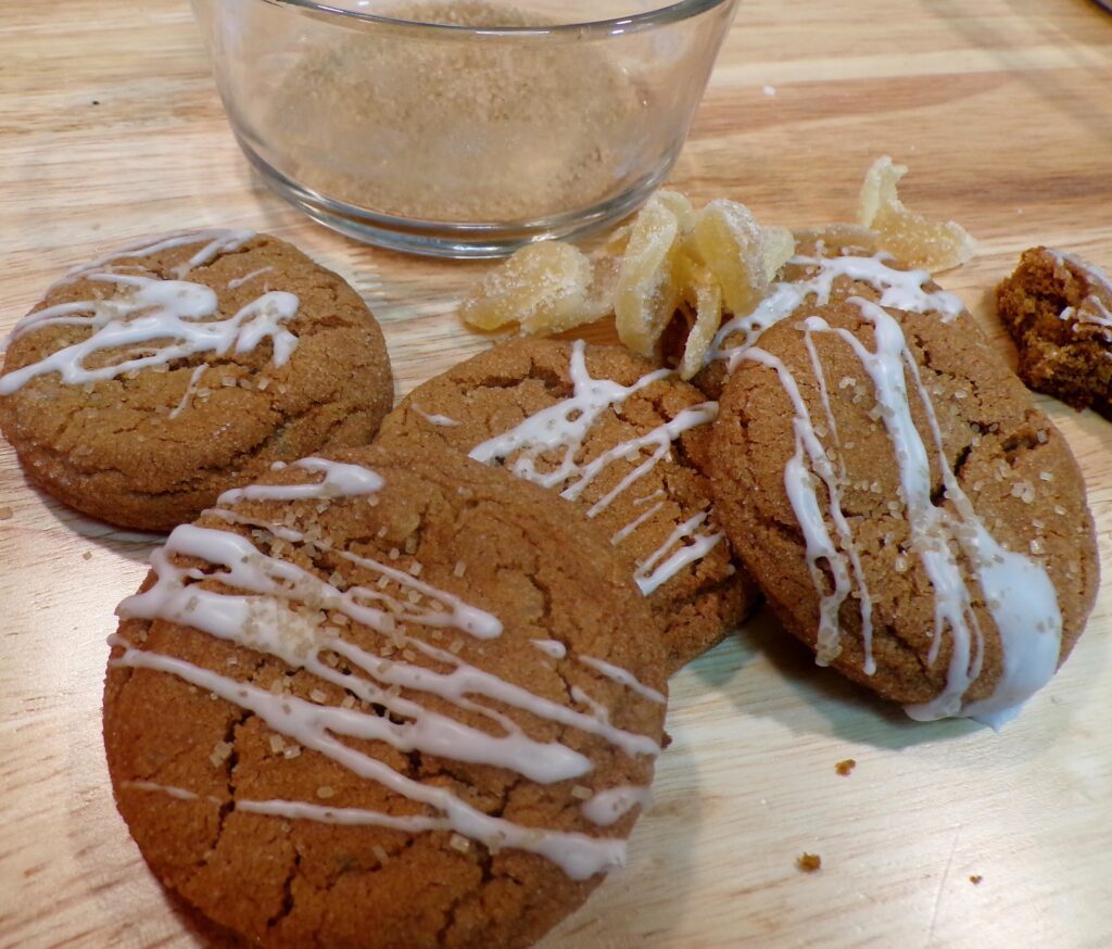 Freshly baked cookies drizzled with white icing on a wooden board.